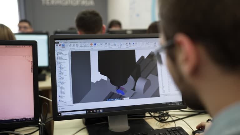 Student learning computer-aided engineering software for CNC machine simulation, demonstrating the role of CAE in digital manufacturing education.