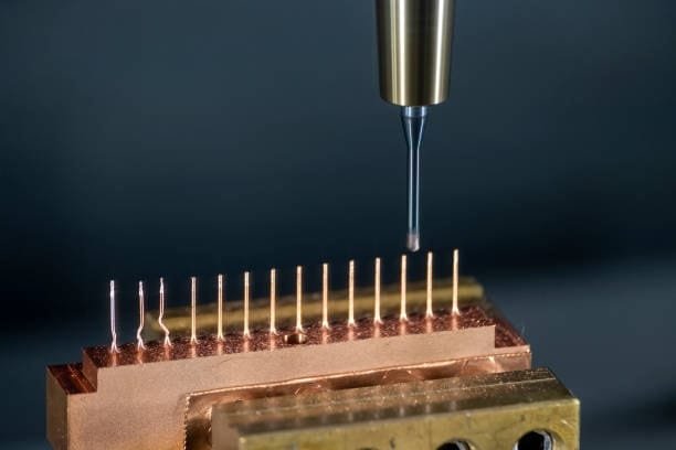 Close-up of a CNC wire electrical discharge machine (EDM) cutting copper material with precision to form thin pins for electronic components.