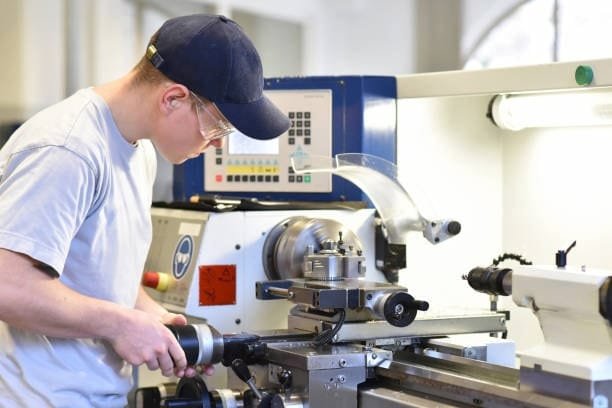 Technician manually adjusting a CNC lathe machine, demonstrating the calibration process before automated operation begins