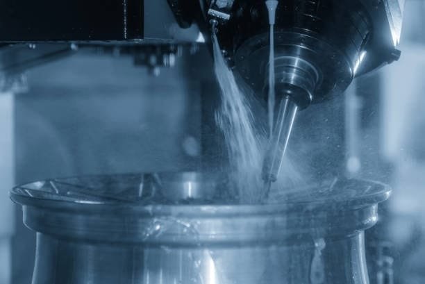 CNC milling machine precision cutting an alloy wheel with coolant being sprayed for lubrication and cooling.