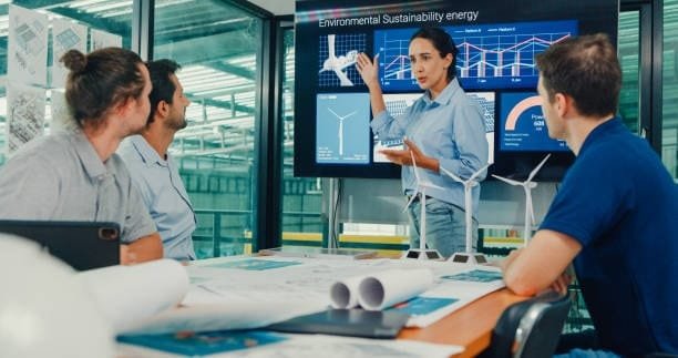 Engineer presenting wind turbine models and environmental data on a digital screen, showcasing the application of computer-assisted design in sustainable energy projects.