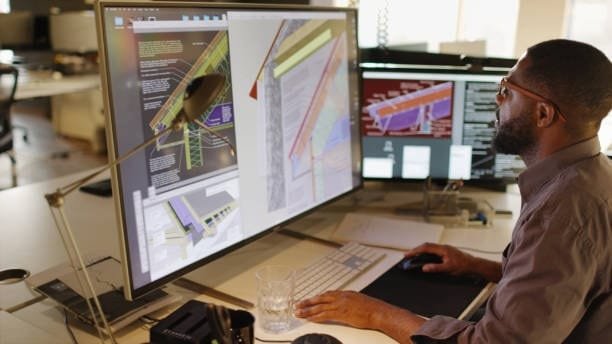 Architect using CAD software on a large monitor to design structural elements, illustrating the precision and efficiency of computer-assisted design in architecture.