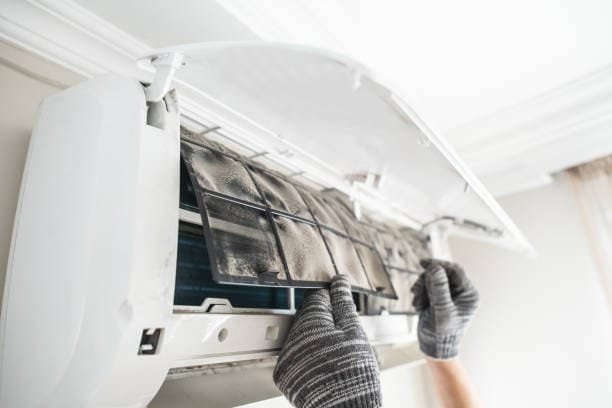 Technician removing air conditioner filters, using a fixture-like setup for maintenance and inspection