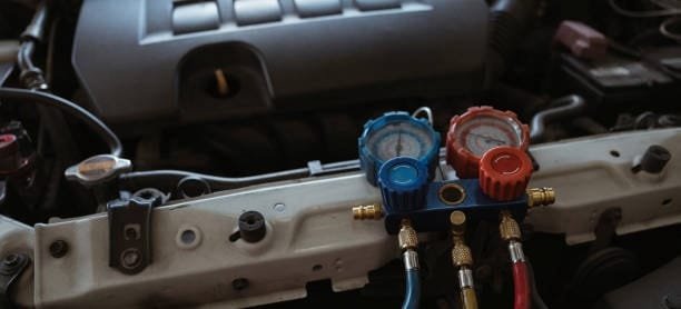Air conditioning gauges placed on a car engine bay as a diagnostic fixture setup for pressure testing
