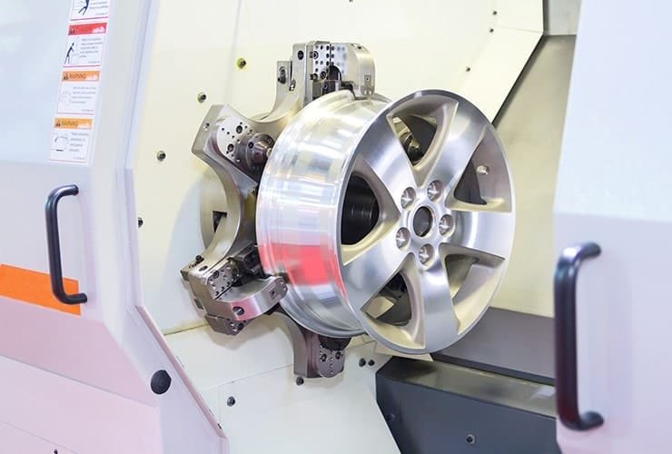 Automotive aluminum wheel rim being precision-machined on CNC lathe.