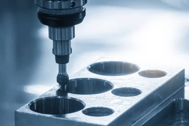 Close-up of a CNC milling machine drilling holes into a metal block, focusing on precision machining and cutting.