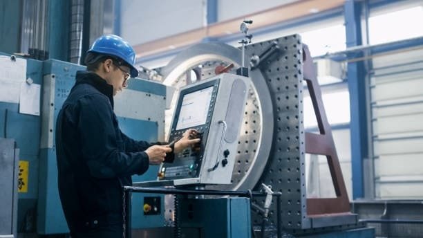 Technician programming a CNC machine in a factory environment, showing real-time control and automation in CNC machining operations.