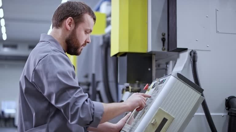 Machinist operating a CNC machine by entering commands into the control interface, representing the final step before starting automated machining.
