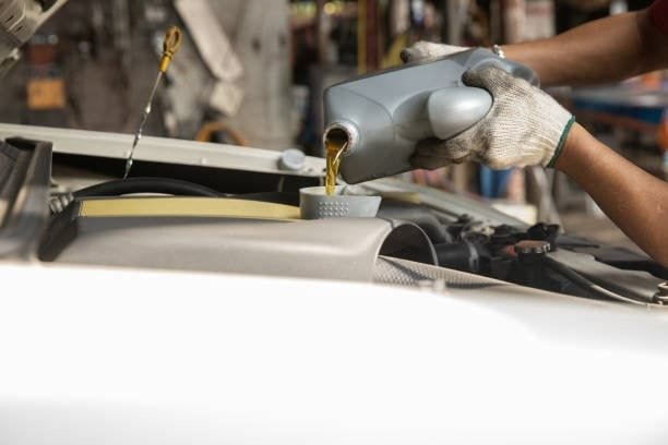 Pouring motor oil into an engine using a funnel as part of a maintenance fixture setup