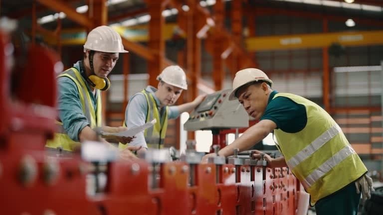 Team of engineers inspecting and monitoring machinery on a production line for quality assurance.