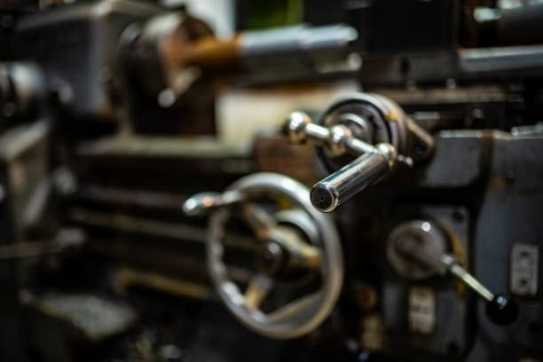 Close-up of manual lathe machine control, contrasting CNC screw machining automation