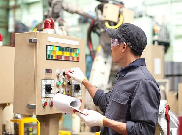 Factory operator monitoring quality control machinery using a control panel.
