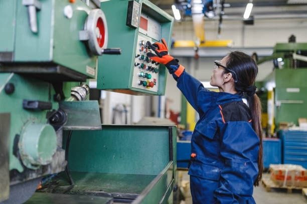 Female operator adjusting settings on a CNC turning machine in a factory.
