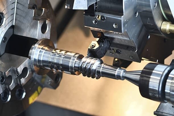 CNC lathe machine performing high-precision screw machining on a metal shaft
