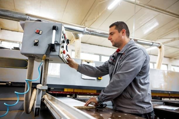 Technician operating industrial machinery and performing quality control adjustments.