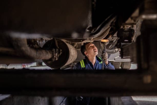 Inspector checking the undercarriage of a truck during quality control inspection.
