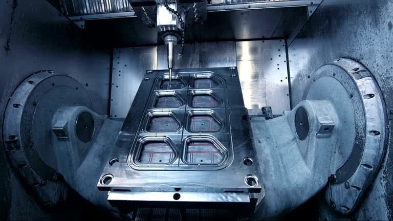 5-axis CNC machine milling multiple cavities into a large mold block.