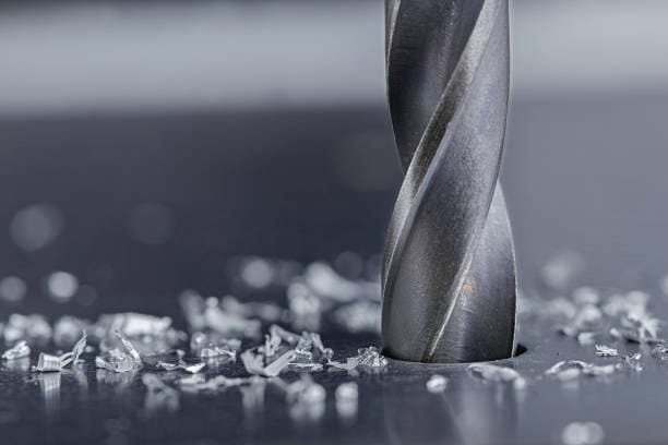 Close-up view of a drilling tool performing machining on a metal surface with metal chips.