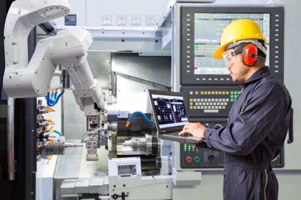 CNC machine operator controlling robotic arms for advanced manufacturing.