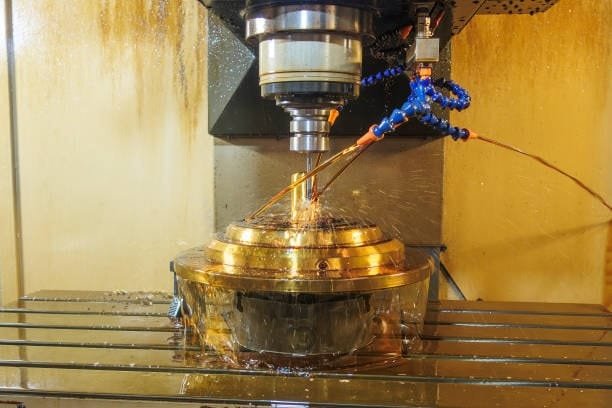 CNC machine spraying cutting fluid for temperature control.
