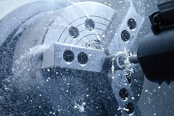 CNC machining process with coolant spray during high-speed metal cutting.