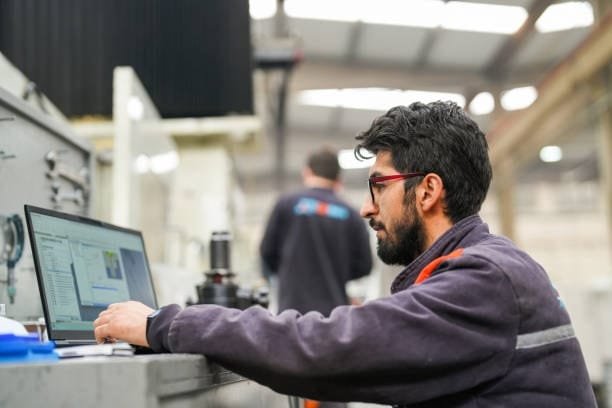 CNC programmer using a laptop to design machining operations.