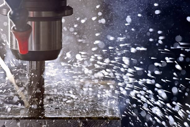 Close-up of coolant being applied during the drilling machining process to prevent overheating.