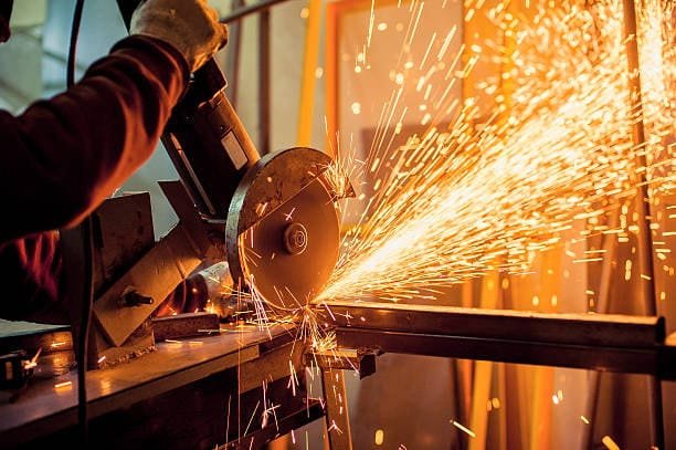 Handheld circular saw cutting metal and producing bright sparks.
