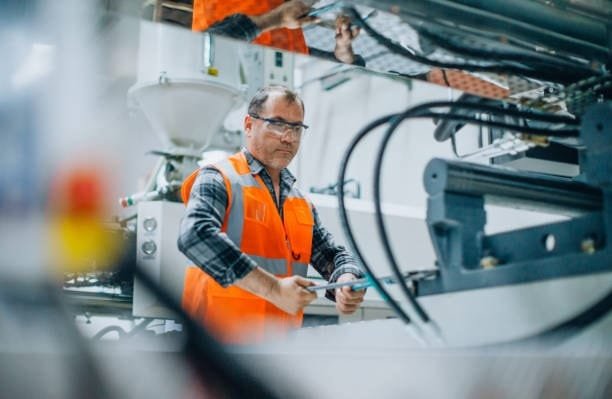 Technician performing maintenance on an industrial drilling machine in a manufacturing facility.