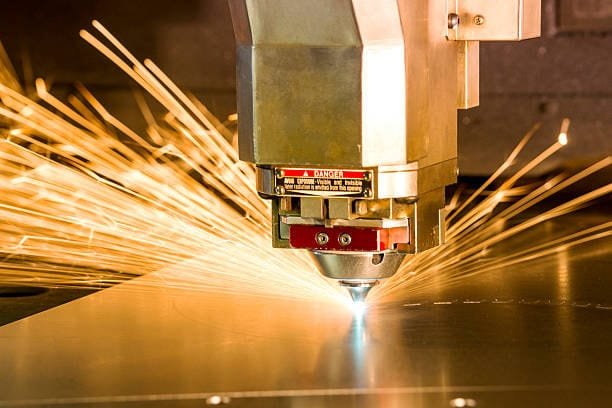 Laser metal cutting machine producing sparks while cutting a steel sheet.