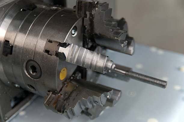Lathe chuck holding a threaded rod for precise cutting operations.