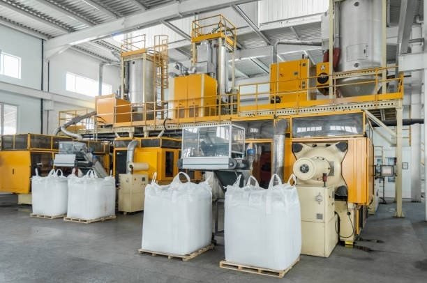 Plastic resin production factory with large bags of raw polymer materials ready for processing.