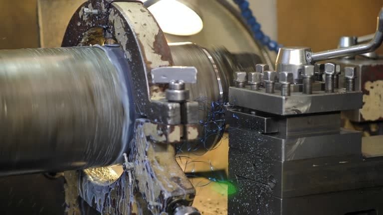 Turning operation on a large metal cylinder using a manual lathe at A-1 Machining