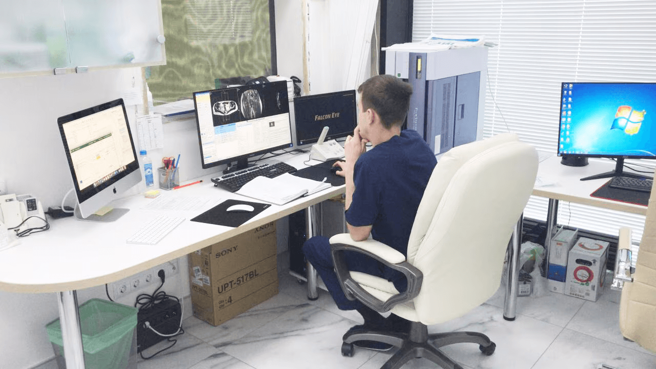 Engineer at workstation reviewing 3D CAD models and specifications on multiple monitors