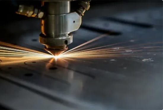 Laser cutting head emitting sparks while cutting complex shapes into a steel sheet