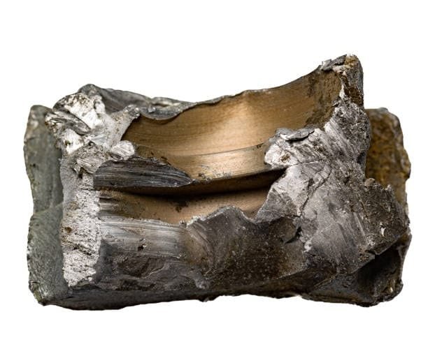 A rugged chunk of raw titanium metal used in industrial hardness testing