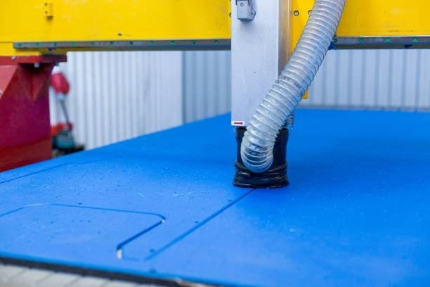 Vacuum table setup with blue spoilboard used for CNC plastic sheet cutting