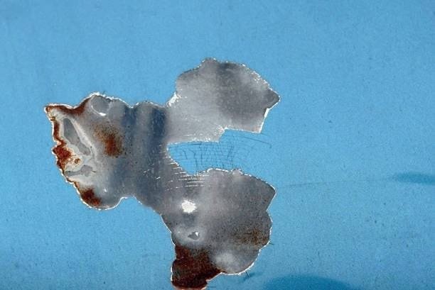 Flaking paint reveals rusted and stripped-down metal surface from corrosion