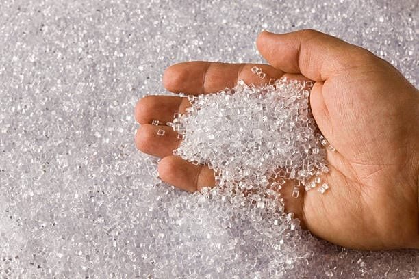 Close-up of hand holding transparent plastic resin granules for molding