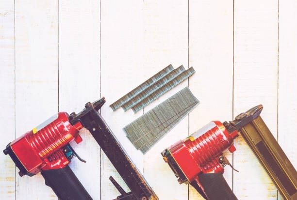 Two red pneumatic nailers with metal staples used in CNC router applications