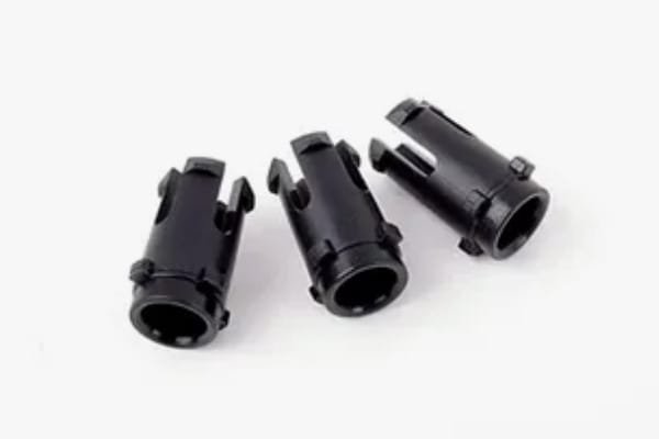 Three black low-volume injection molded plastic parts with precise geometric features