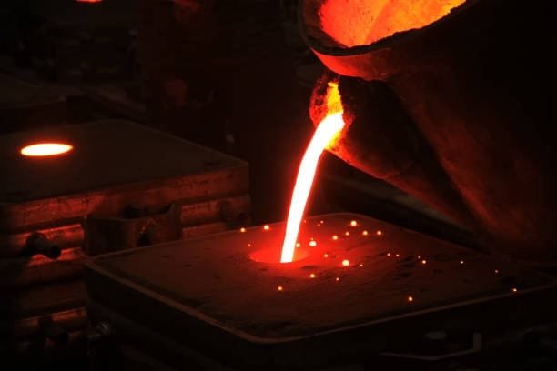 Molten metal being poured into a sand mold in a metal casting process