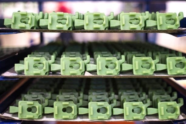 Green plastic molded parts arranged on trays for post-processing