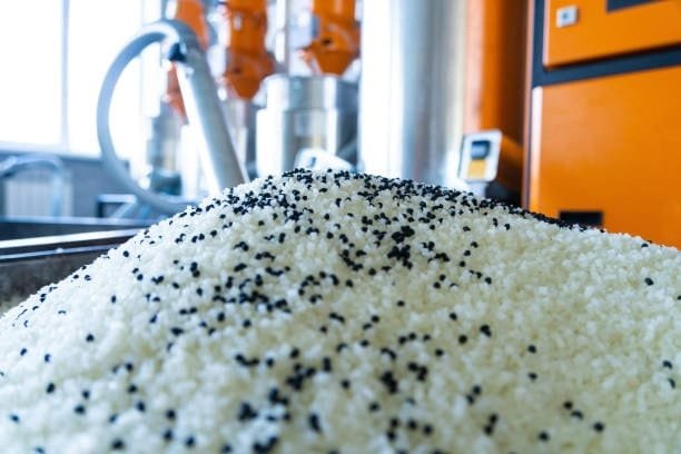 White and black plastic granules piled for processing in an injection molding plant