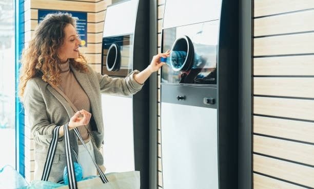 Woman placing plastic bottles into recycling machine for reuse in molding