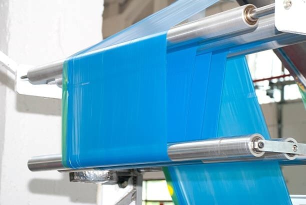 Blue plastic film being extruded and rolled in molding facility