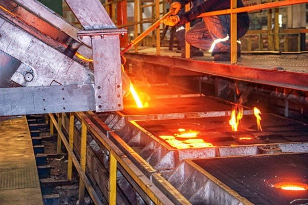 Worker pouring molten metal into sand casting molds