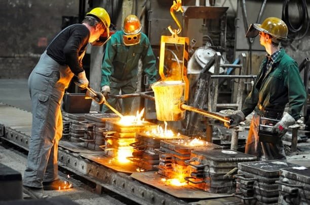 Foundry workers performing metal casting operations with protective gear